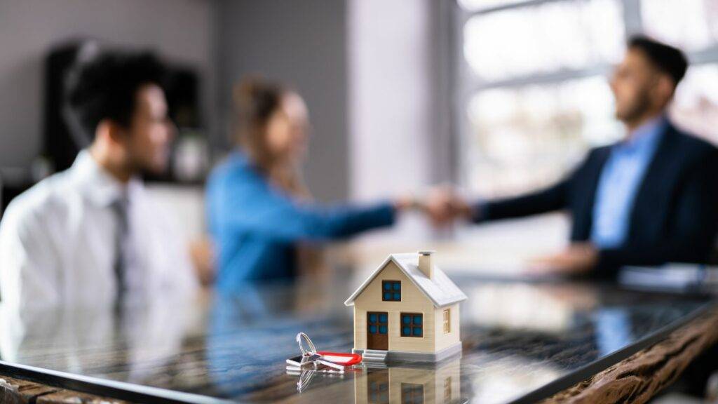 Wealth management consultation with house model and keys representing private client tax advisory services for high-net-worth individuals.